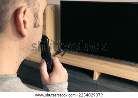 man talking to the tv remote to interact with the television