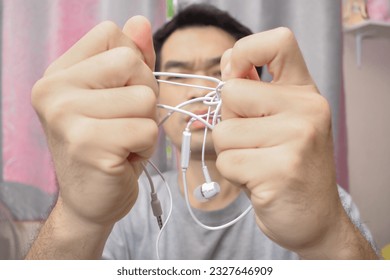 Man with tangled headphones isolated white background