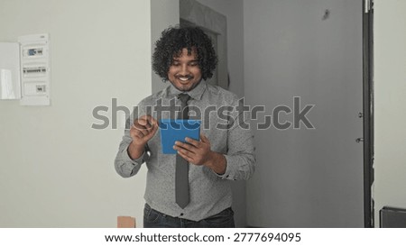 Man tapping blue tablet with hands inside a building during an empty house walkthrough; confidence property viewing.