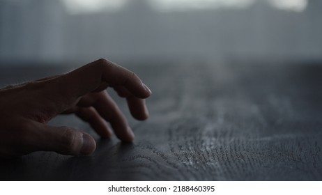 Man Tapping Fingers On Black Oak Table With Back Light, Wide Photo