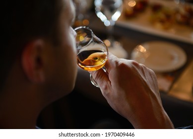 Man tasting cognac holding glass close to nose smelling the aroma