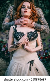 Man With Tattoo Holding Woman Neck In Hand. Couple Near Decorated Arch. Fairytale Story Concept.
