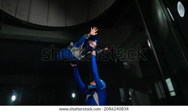 A man teaches\
a boy to fly in a wind\
tunnel.
