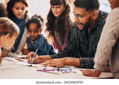 Man teaches his students how to draw in a primary school class. This elementary school educator shows his kids how to use a colouring pencil. Teaching an elementary class in a multiethnic school. - Powered by Shutterstock