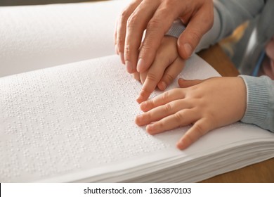 Man teaching child to read book written in Braille, closeup - Powered by Shutterstock