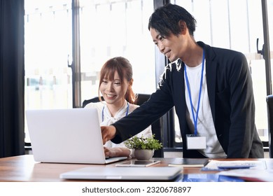 A man teaching a computer in the office and a young woman being taught