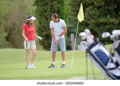 Man Teaching A Woman How To Play Golf