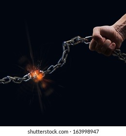 man tearing a heavy steel chain by hands as a conceptual symbol of freedom