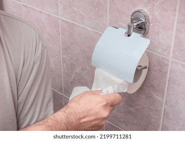 The man tears off a sheet of toilet paper - Shutterstock ID 2199711281
