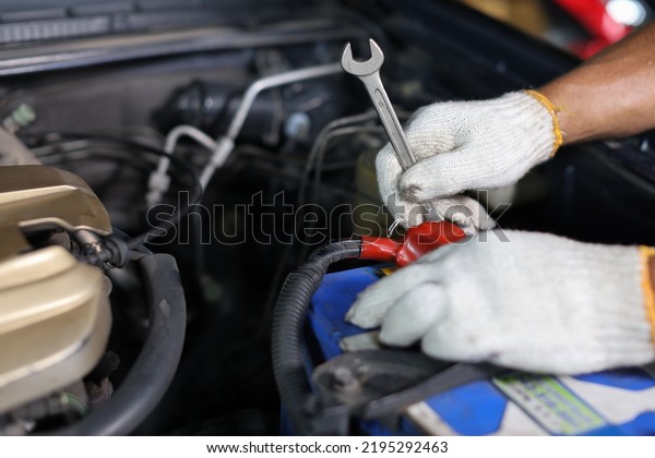 Man technician car mechanic hamds in half\
uniform checking maintenance a car service at repair garage\
station. Worker holding wrench and fixing breakdown vehicle.\
Concept of car center repair\
service.