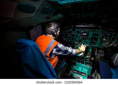 A man is a technician at the helm of an old passenger plane. Inside the cockpit