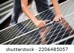 Man technician mounting photovoltaic solar moduls on roof of house. Close up of electrician installing solar panel system with help of hex key. Concept of alternative and renewable energy.