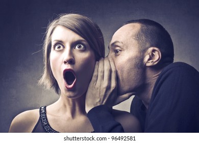 Man telling an astonished woman some secrets - Shutterstock ID 96492581