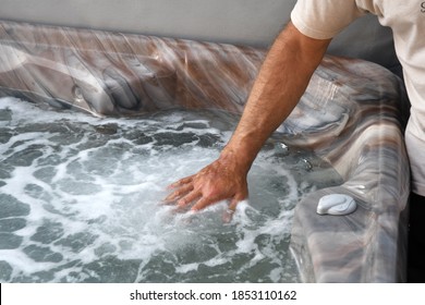 A Man Test The Water Temperature In A Hot Tub.