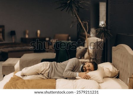 a man is testing and lying on a bed in a furniture store