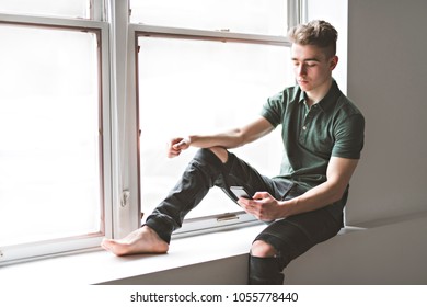 Man texting sit ont the window border