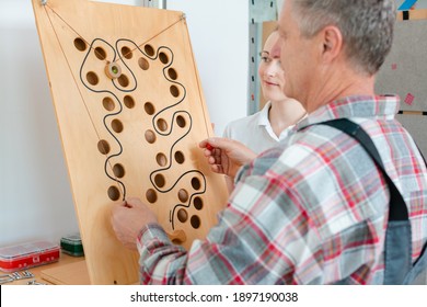 Man with therapist in occupational therapy testing his dexterity on a game board