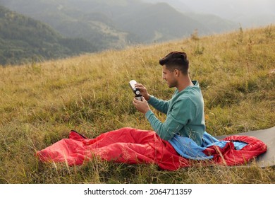 Man With Thermos In Sleeping Bag On Hill, Space For Text