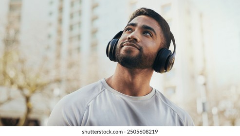 Man, thinking and city with headphones for music, listening or audio streaming in an urban town. Young male person in wonder for outdoor inspiration or dream with headset for sound, podcast or radio - Powered by Shutterstock