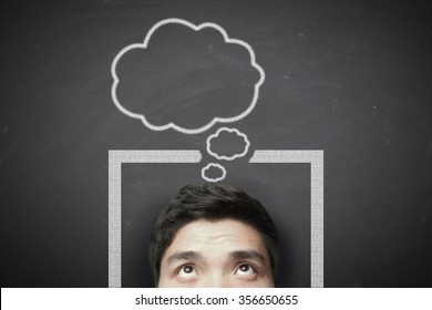 Man Thinking Outside The Box With Blackboard Background.