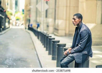 Man Thinking Outside. Young Black Teenage Boy Is Sitting On Street, Hunchbacked, Sad, Tired, Looking Down, Thinking, Lost In Thought. Retro Filtered Look.
