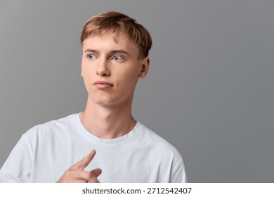 Man, thinking, thoughtful expression with sideways gaze in a casual white shirt, studio shot, minimal backdrop, modern mood, clean lighting, calm posture, subtle everyday vibe