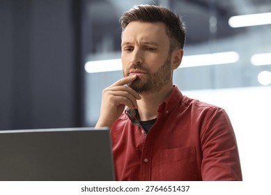 Man Thinking While Working on Computer in Modern Office Setting During Day Hours