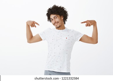 Man thinks girlfriend lucky to have him. Portrait of confident and cute flirty hipsanic boyfriend with afro haircut and moustache pointing at himself and smiling broadly, proud of his ahievements