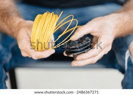 Man threading line into trimmer head of grass trimmer - step by step instructions