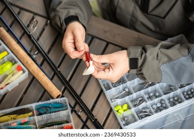 a man threads a fishing hook into a rubber bait, fishing, spinning, preparation for fishing, wobblers, fishing lures - Powered by Shutterstock