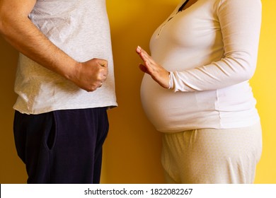 Man Threatening Pregnant Woman With Fist, But She Try To Defense. Domestic Abuse. Pregnant Woman Suffering From Home Violence. Social Problems Of The Family. Pregnant Woman Abused By Her Husband.