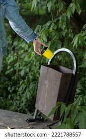 Man Throw Away A Paper Cup Into The Urn. Hand Throws Glass. Old Trash Can. Broken Trash Can