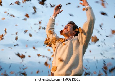 Man Throwing Autumn Leaves In Air