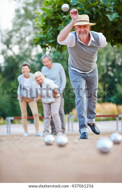 Man\
throwing ball while playing boule outside in a\
city