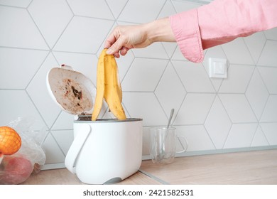 Man throwing banana peel into countertop composter. Concept of home composting, converting kitchen biodegradable waste into compost at home. - Powered by Shutterstock