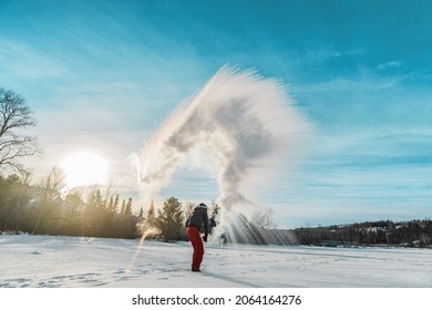Man throwing boiling hot water freezing mid air. Or rather, the water disperse, vaporize and condensate like a cloud. Some of the water condensate freezes and forms ice crystals. Shot at -29 Cn -20F.