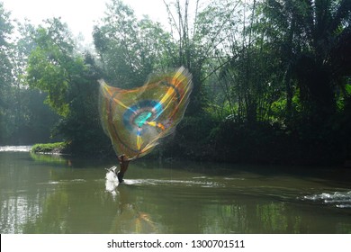 A man is throwing the fishnet to catch the fish in the river