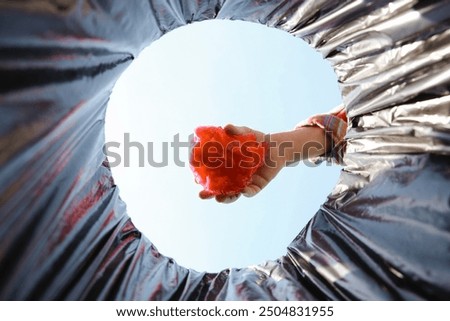Man throwing garbage into trash bin outdoors, bottom view