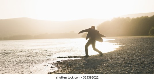 Man Throwing Pebbles In A River 