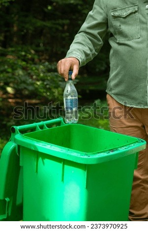  Man throwing plastic bottle into trash bin.
