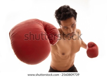 Man throwing punch in the air while wearing boxing gloves in front of a white background,