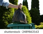 Man throwing trash bag into bin outdoors, closeup