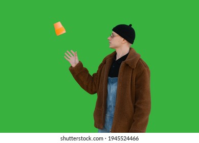 Man With A Thrown Reusable Coffee Cup On A Background Of A Green Wall