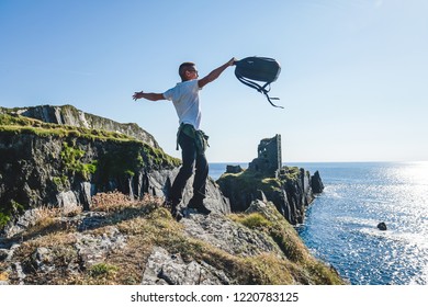 Man throws up a backpack on the background of the ruins of the fort