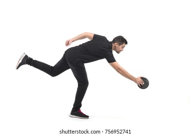 The man throws the disc. Athlete in black clothes. In the bent position. On one leg. White background. Isolated object. - Powered by Shutterstock