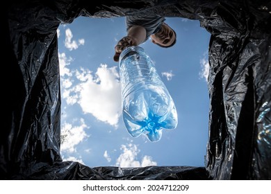 A Man Throws Empty Plastic Bottle Into A Trash Can. Bottom View From The Trash Can. The Problem Of Recycling And Pollution Of The Planet With Garbage.