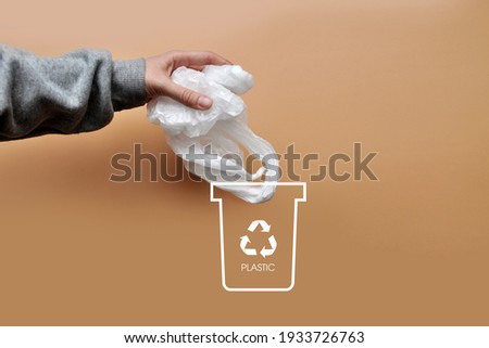 A man throws a plastic bag into a dumpster. Sorting and recycling of garbage