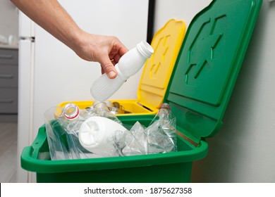 The man throws the plastic bottle to the one of three container for sorting garbage - Shutterstock ID 1875627358