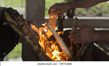 A man throws a tree into the fire close up