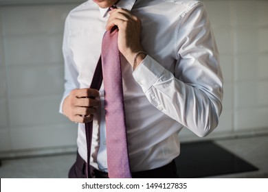 man in a tie, the groom tightens his tie, man puts on a purple tie, purple tie, wedding day, groom's morning